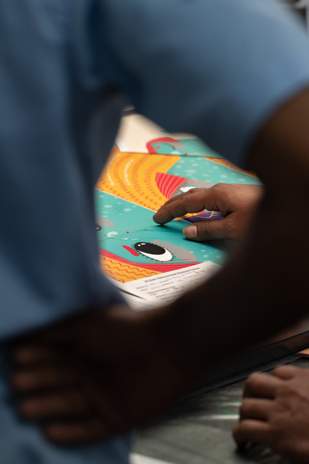 Hands lifting a freshly printed sheet off the stack