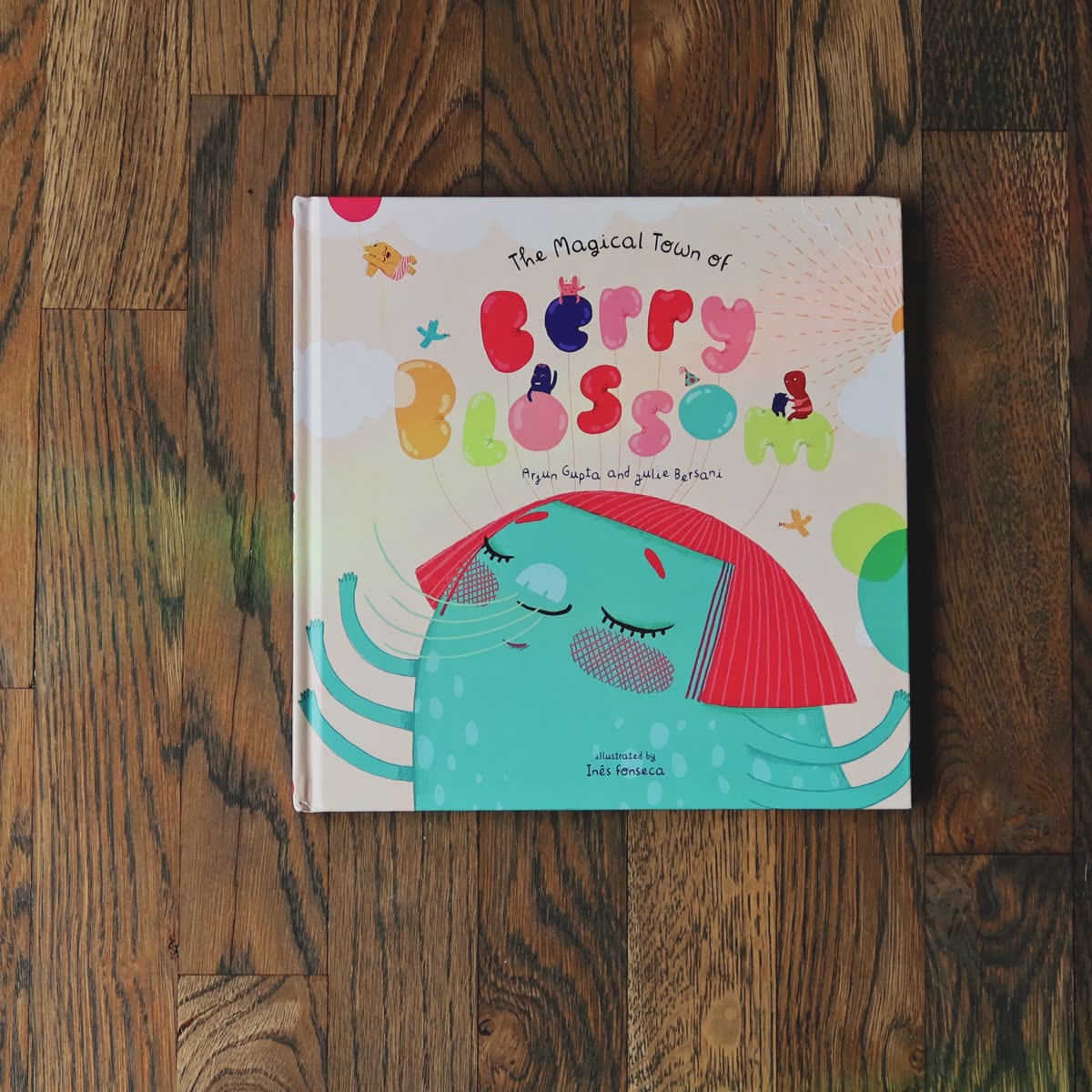 The hardcover lying face up on a wooden floor