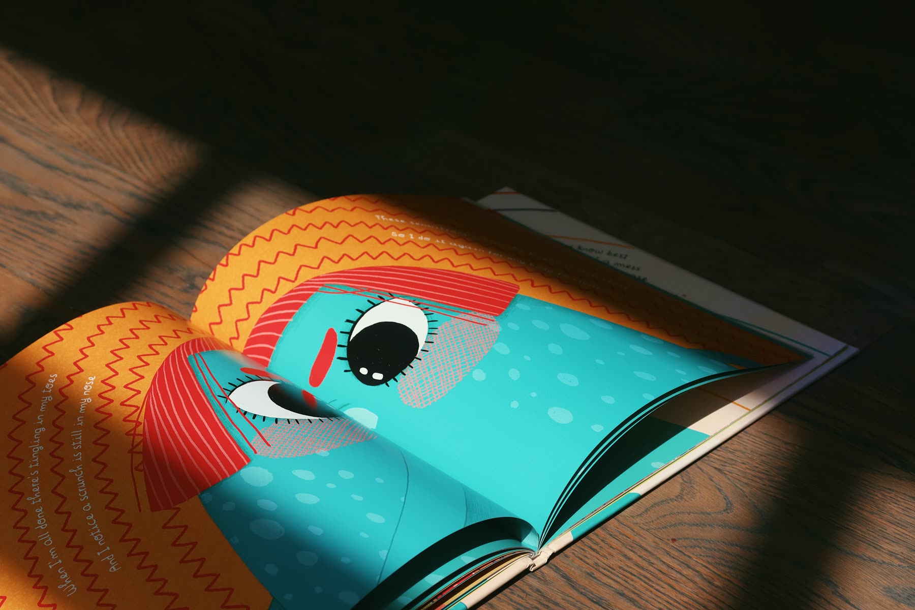 An open spread in slatted afternoon light, close on an orange and teal character's eye