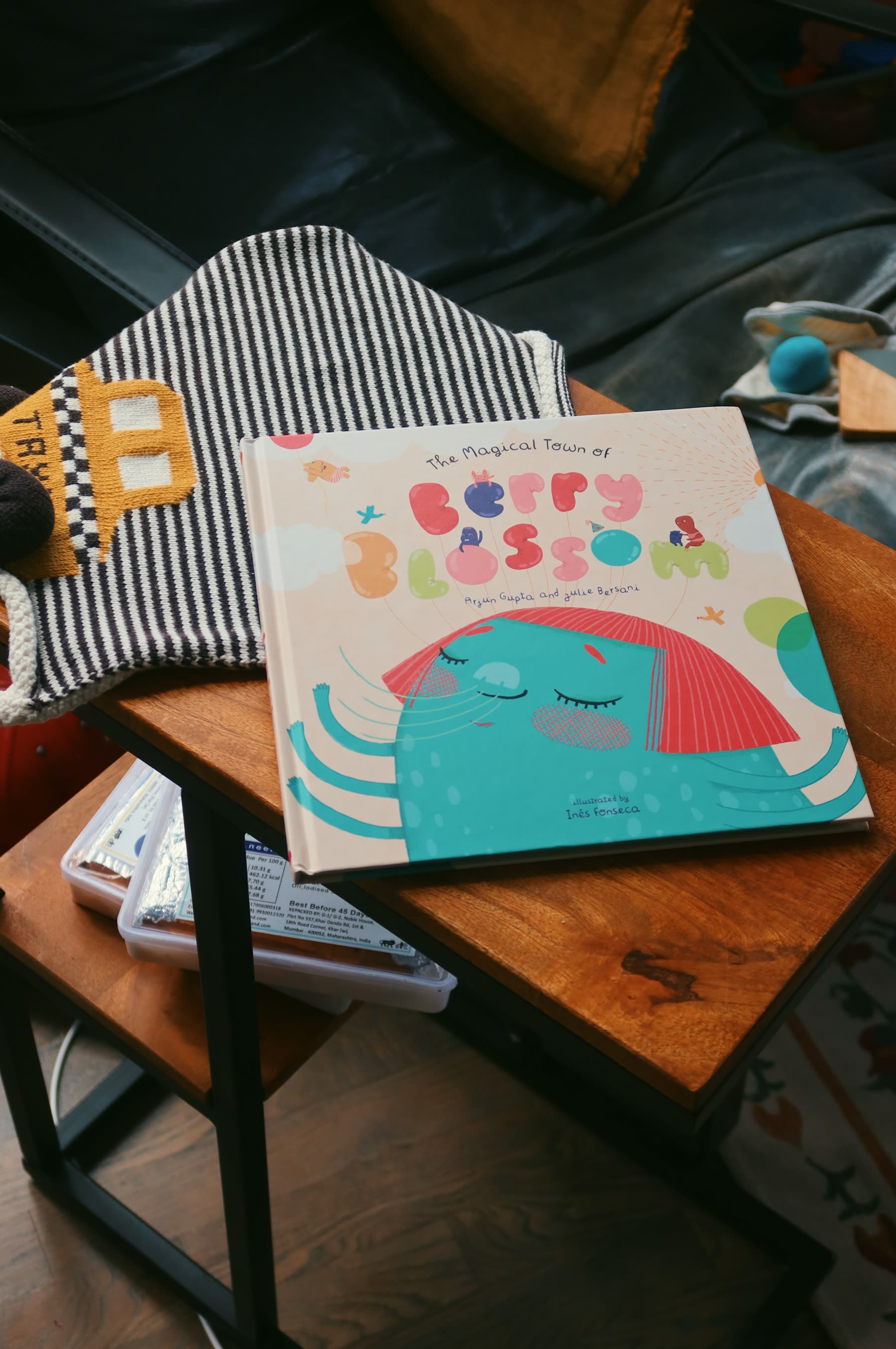 The book propped upright on a small wooden table beside a striped cushion