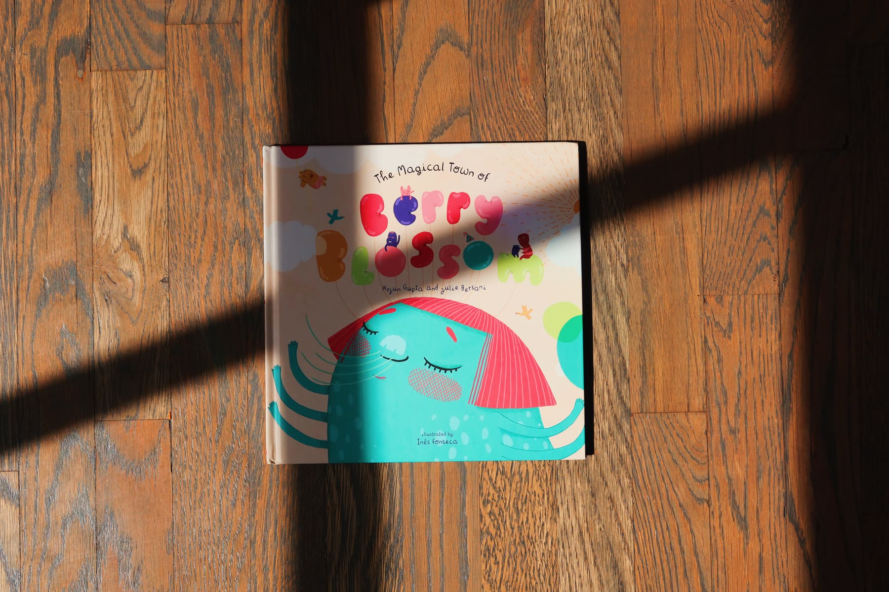 The closed hardcover on a wooden floor with window shadows falling across it